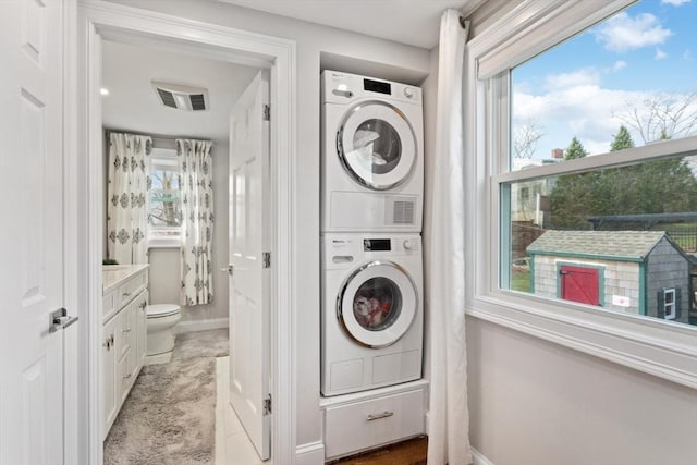 clothes washing area featuring stacked washing maching and dryer