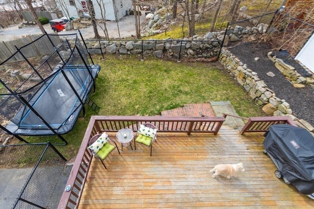 wooden terrace featuring a trampoline, area for grilling, and a lawn