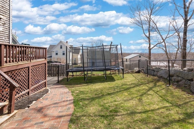 view of yard with a trampoline and a wooden deck