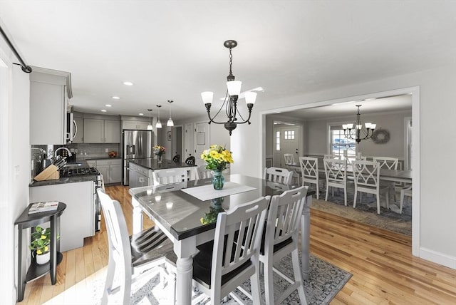 dining room with an inviting chandelier, crown molding, recessed lighting, and light wood-type flooring