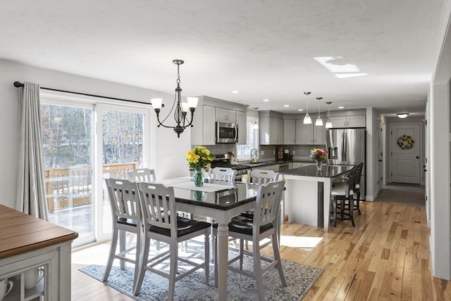 dining room with recessed lighting, an inviting chandelier, and light wood finished floors