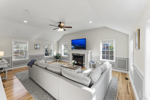 living area featuring a premium fireplace, plenty of natural light, light wood-style floors, and vaulted ceiling