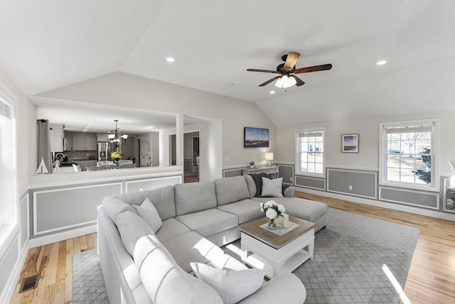 living room featuring light wood finished floors, visible vents, and vaulted ceiling