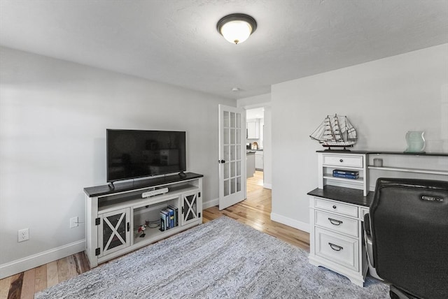 office with french doors, baseboards, and light wood-style flooring