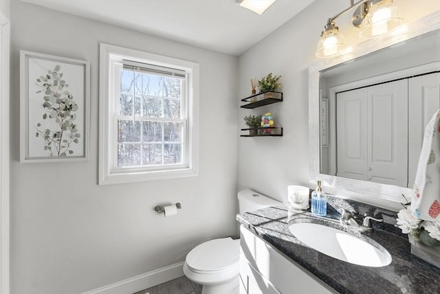 bathroom with toilet, vanity, and baseboards