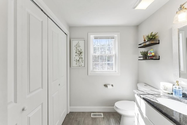 bathroom with vanity, wood finished floors, visible vents, baseboards, and toilet