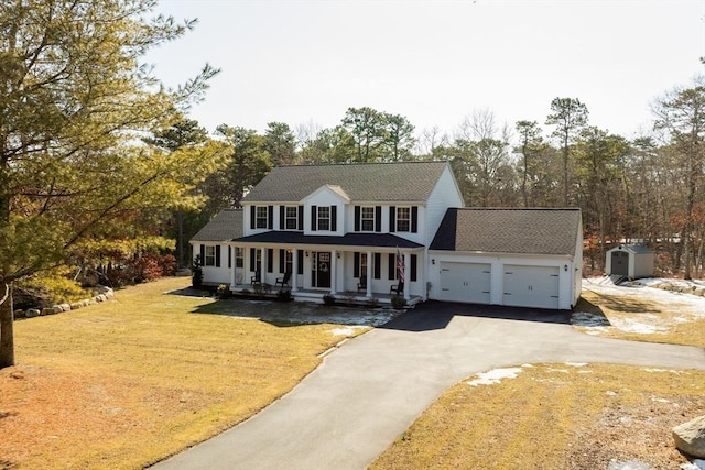 view of front facade with aphalt driveway, a porch, a garage, and a front lawn