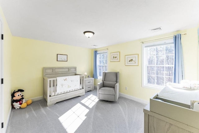 bedroom featuring a nursery area, carpet flooring, baseboards, and visible vents