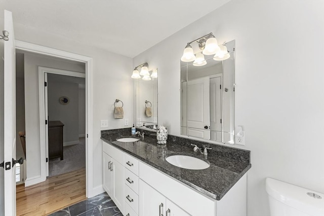 bathroom featuring a sink, baseboards, toilet, and double vanity