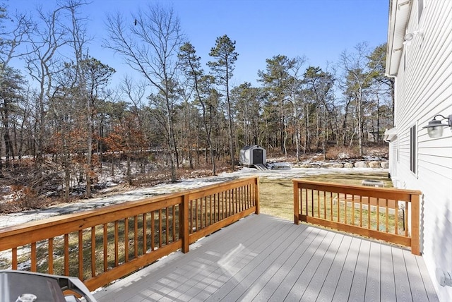 snow covered deck with a storage shed and an outdoor structure