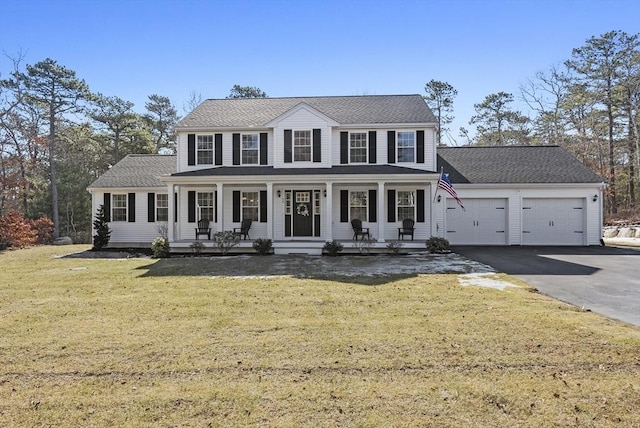 colonial home featuring aphalt driveway, a garage, a porch, and a front yard