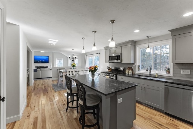 kitchen with a sink, stainless steel appliances, tasteful backsplash, and gray cabinetry