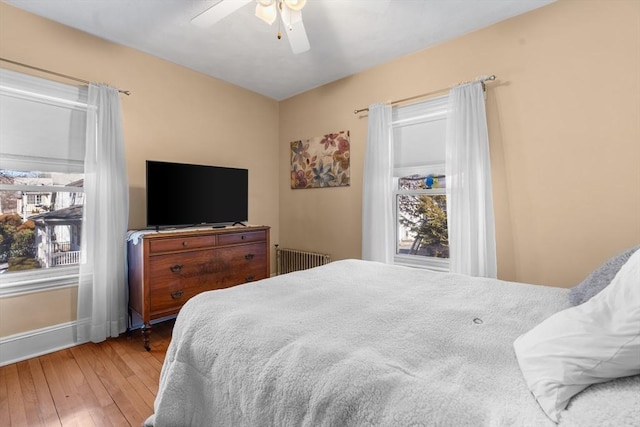 bedroom featuring radiator, hardwood / wood-style floors, and ceiling fan