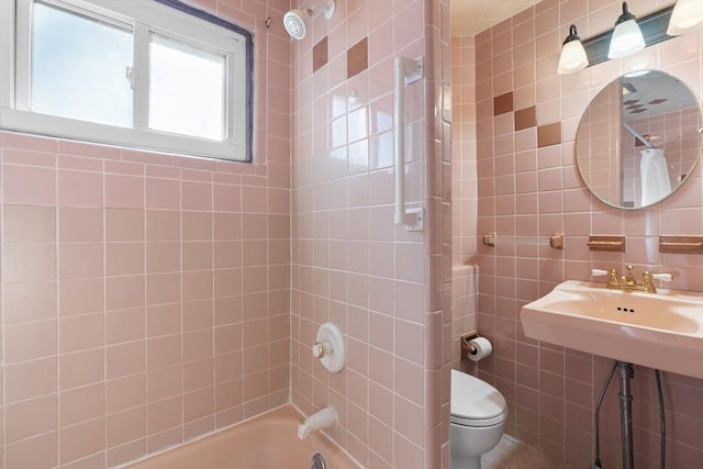 bathroom with tiled shower / bath, tile walls, and toilet