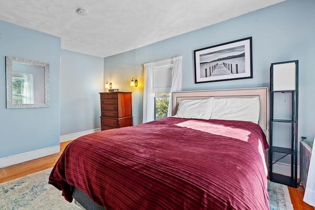 bedroom featuring radiator and light hardwood / wood-style floors