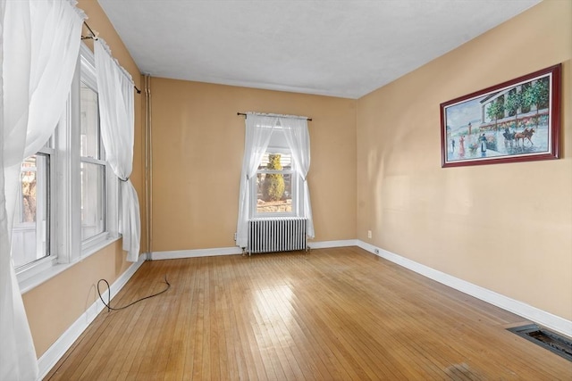 unfurnished room featuring light hardwood / wood-style flooring and radiator heating unit