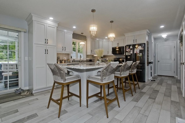 210 Naismith, Springfield, MA 01104 - kitchen with black appliances, white cabinets, a chandelier, light wood-style floors, and light stone countertops