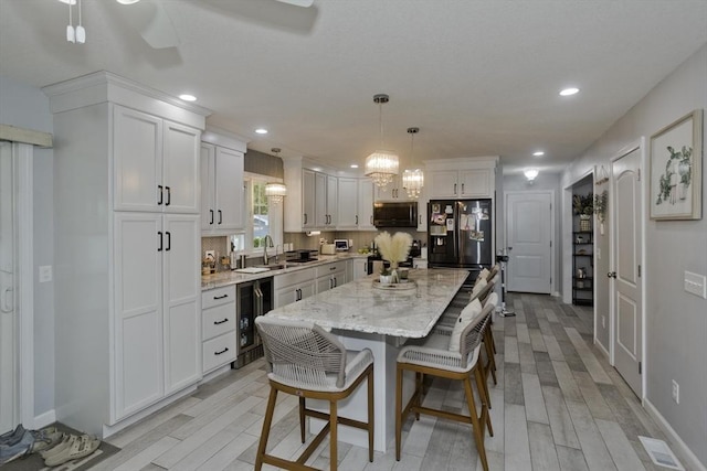 210 Naismith, Springfield, MA 01104 - kitchen with stainless steel microwave, black fridge, white cabinetry, wine cooler, and light wood finished floors