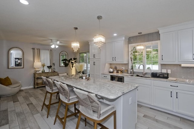 210 Naismith, Springfield, MA 01104 - kitchen with a chandelier, a breakfast bar, white cabinetry, a center island, and tasteful backsplash