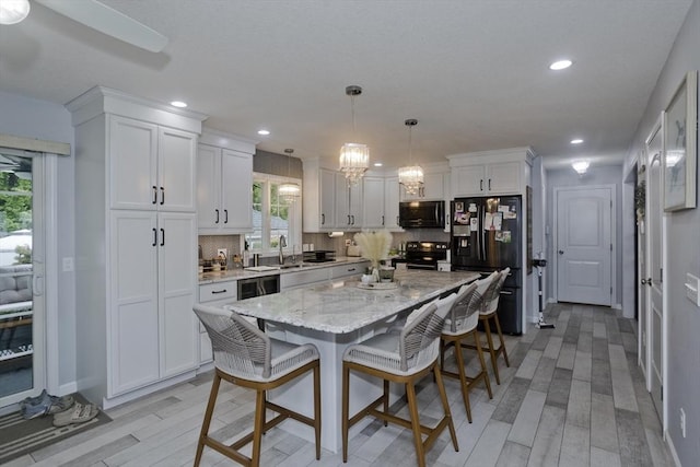 210 Naismith, Springfield, MA 01104 - kitchen featuring black appliances, a breakfast bar, white cabinetry, light wood finished floors, and recessed lighting