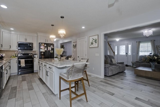 210 Naismith, Springfield, MA 01104 - kitchen featuring electric range oven, black fridge, stainless steel microwave, open floor plan, and a breakfast bar area