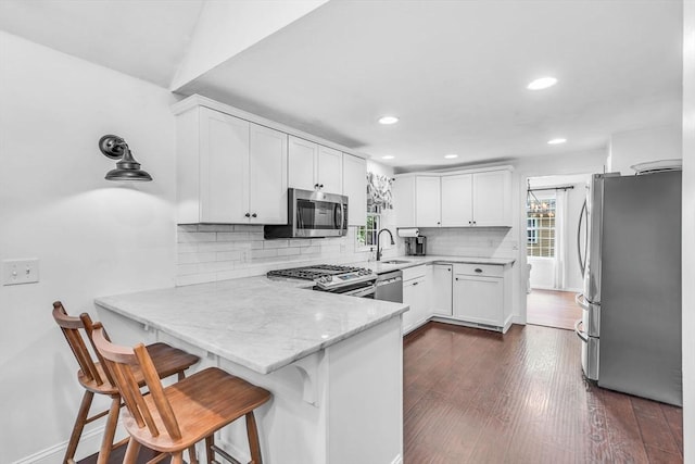 12 Blueberry Ln, Hudson, MA 01749 - kitchen featuring appliances with stainless steel finishes, a sink, a peninsula, decorative backsplash, and white cabinets