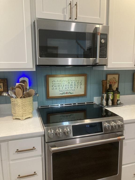 8 Salisbury Hill Blvd Unit 76, Worcester, MA 01609 - kitchen with stainless steel appliances, white cabinets, light countertops, and decorative backsplash