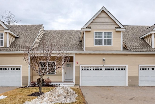 view of front facade with driveway and a shingled roof