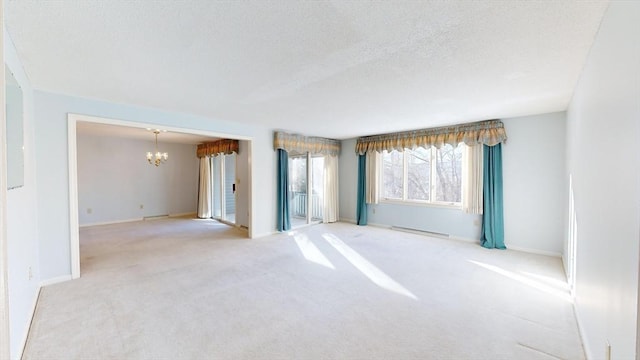 carpeted spare room with a textured ceiling and a notable chandelier