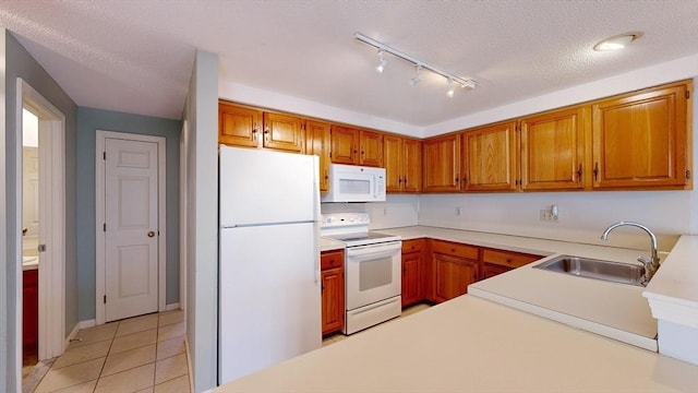 kitchen with sink, white appliances, light tile patterned floors, and a textured ceiling