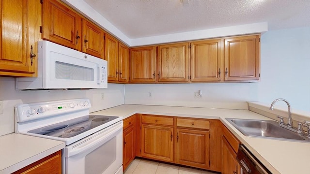 kitchen with white appliances, sink, a textured ceiling, and light tile patterned floors