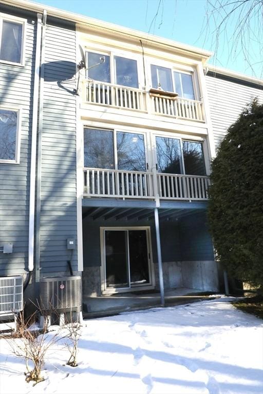 snow covered rear of property featuring a balcony and cooling unit