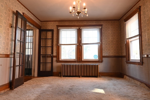 carpeted empty room with crown molding, an inviting chandelier, and radiator