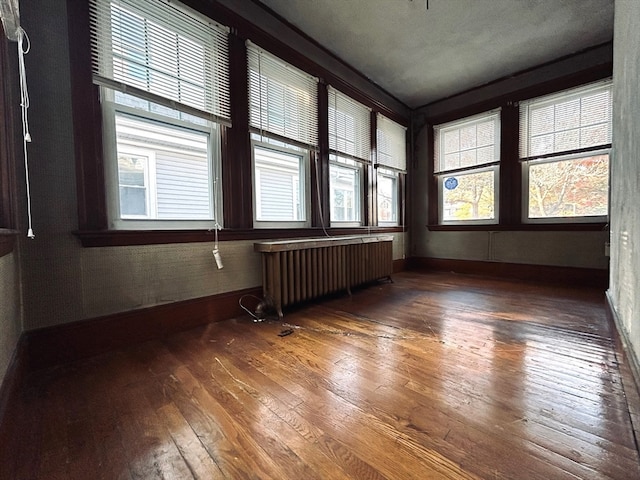 empty room featuring dark wood-type flooring and radiator