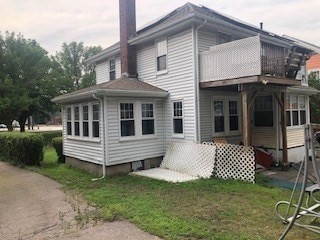 back of house featuring a balcony and a yard