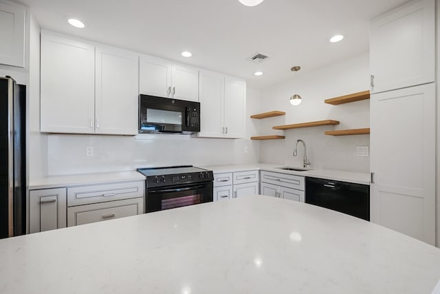 kitchen with hanging light fixtures, black appliances, white cabinetry, and sink