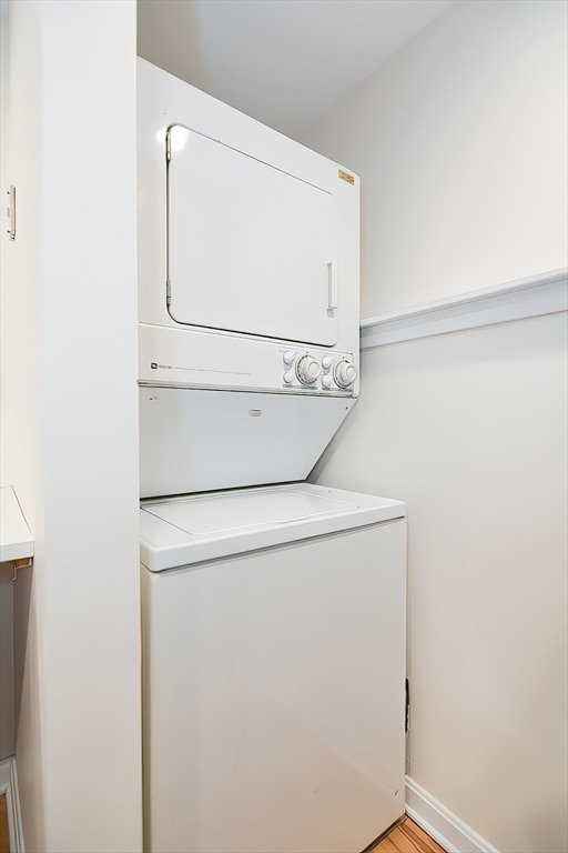 laundry area featuring light hardwood / wood-style floors and stacked washer and clothes dryer