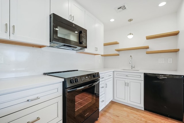 kitchen featuring hanging light fixtures, black appliances, sink, and white cabinetry