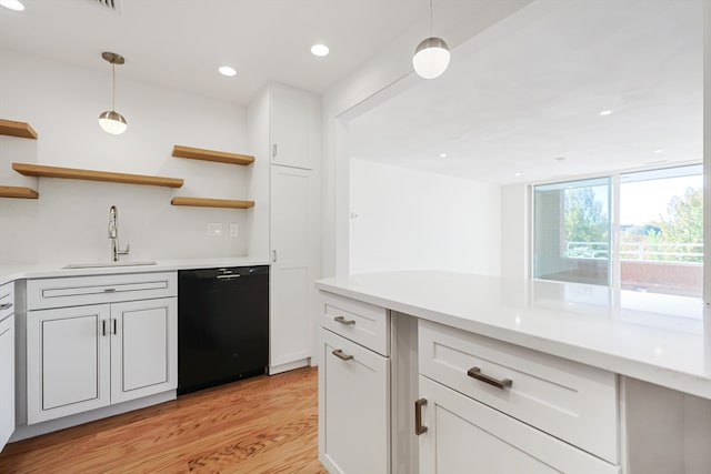 kitchen featuring white cabinets, sink, black dishwasher, light hardwood / wood-style flooring, and decorative light fixtures