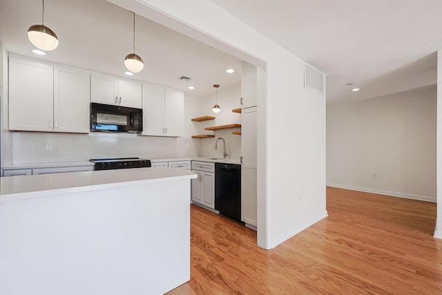 kitchen with light wood-type flooring, sink, hanging light fixtures, white cabinets, and black appliances