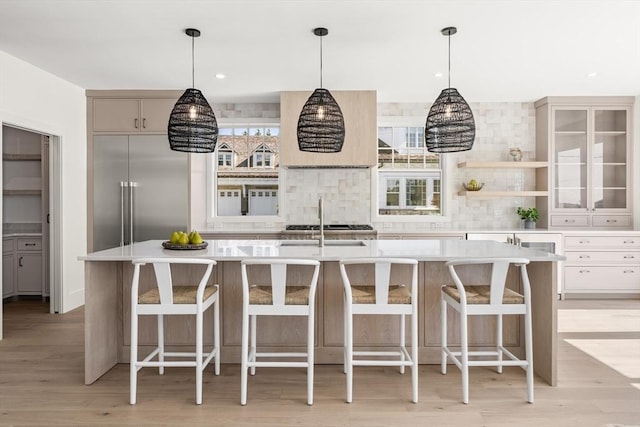 2 Collier Rd, Scituate, MA 02066 - kitchen with built in refrigerator, light countertops, decorative backsplash, light wood-type flooring, and a kitchen island with sink