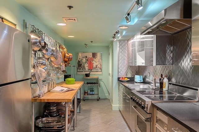 kitchen featuring stainless steel appliances, sink, decorative backsplash, and exhaust hood