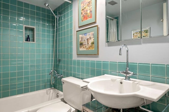 full bathroom featuring tiled shower / bath, toilet, sink, and tile walls