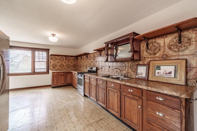 kitchen featuring appliances with stainless steel finishes, a sink, brown cabinetry, baseboards, and light floors