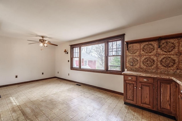 empty room featuring baseboards, a ceiling fan, and light flooring
