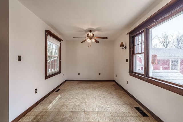 empty room featuring healthy amount of natural light, baseboards, and ceiling fan