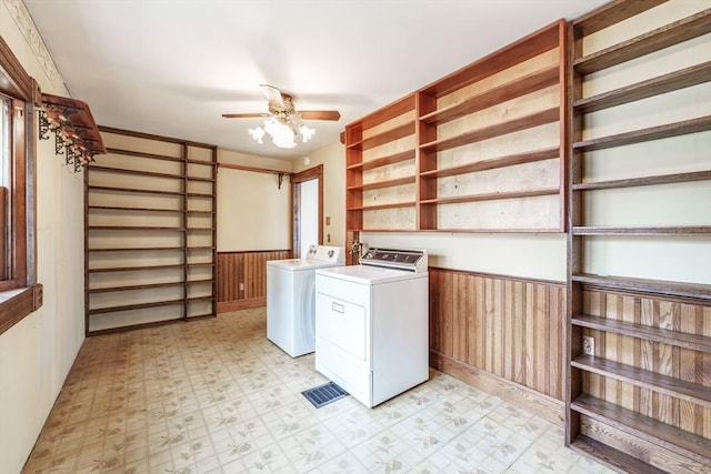 laundry room featuring independent washer and dryer, light floors, ceiling fan, wainscoting, and wood walls