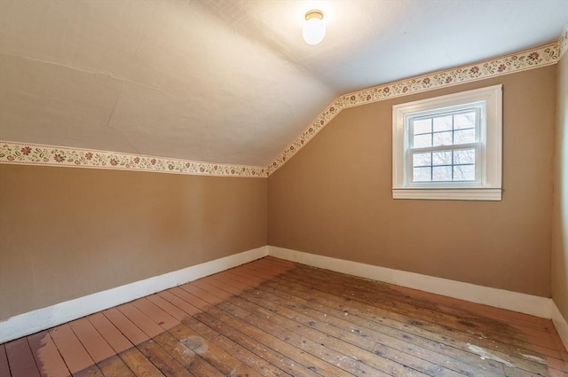 additional living space with hardwood / wood-style floors, baseboards, and vaulted ceiling