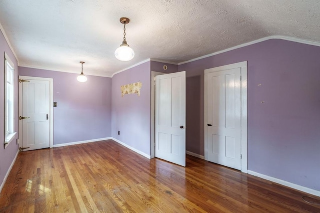 spare room with wood finished floors, a textured ceiling, baseboards, and ornamental molding