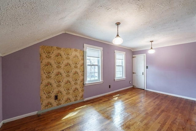 additional living space featuring a textured ceiling, wood finished floors, baseboards, and vaulted ceiling